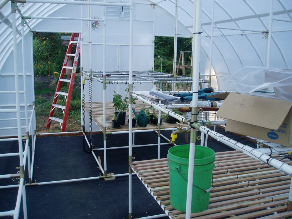 Benches in the greenhouse using PVC tubing and metal fittings. Topped with wood slats and plastic mesh